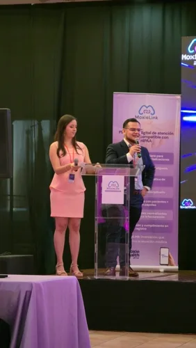 The hosts open Moxiethon 2025 from the podium, beside the MoxieLink stand.