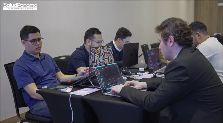 A five person team codes together, screens lit with editor windows.