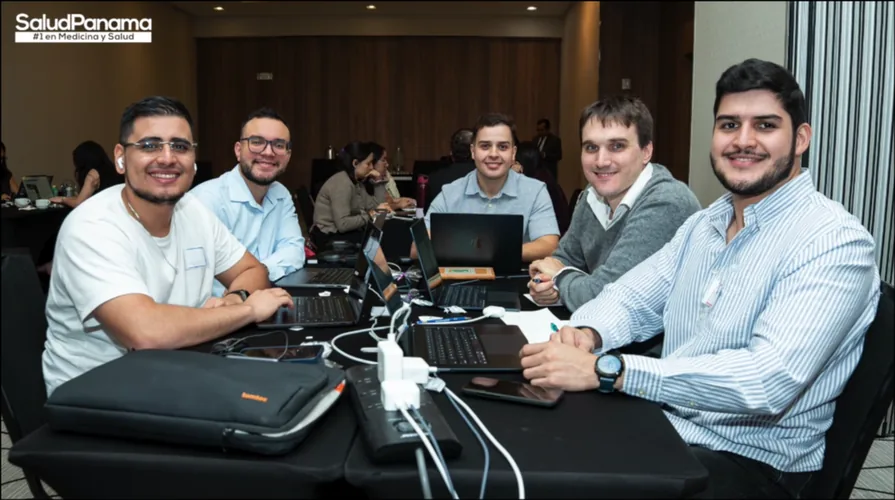 Five engineers gather around a table of laptops mid-session.
