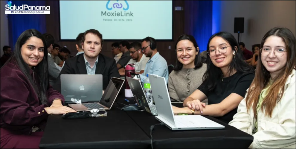 A team poses at their table, laptops open, the MoxieLink Panama On-Site 2026 slide on screen behind them.