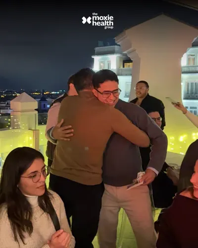 Colleagues share a hug during an evening gathering.